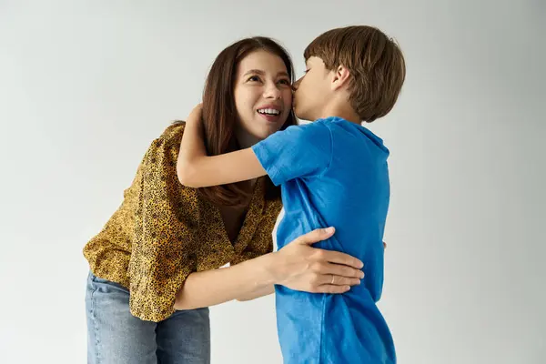 Une interaction joyeuse se déroule alors qu'une mère partage un câlin tendre avec son jeune fils en studio. — Photo de stock