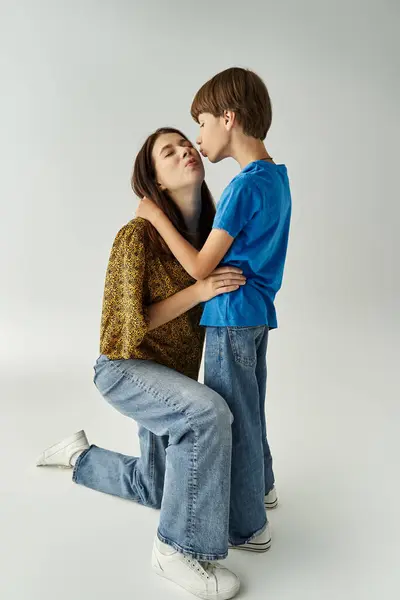 A young mother shares a tender moment with her son in casual attire while kneeling together. — Stock Photo