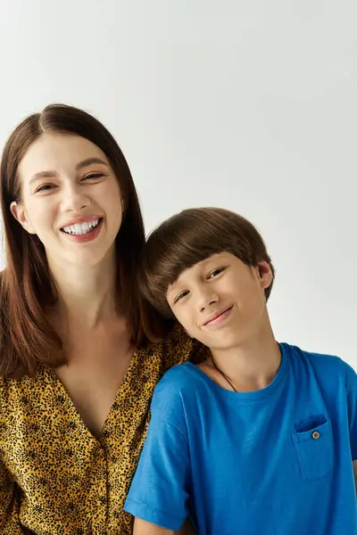 A joyful young mother and her smiling son pose closely together in a modern studio. — Stock Photo