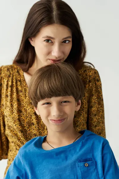 Une jeune mère embrasse doucement son fils pendant qu'ils partagent des sourires dans un studio lumineux. — Photo de stock