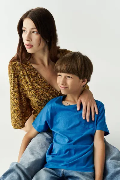 A young mother sits with her son, both wearing casual clothes, radiating joy and connection. — Stock Photo