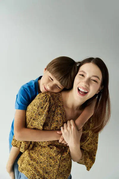 Una joven madre abraza alegremente a su hijo en un estudio contemporáneo, capturando su vínculo. - foto de stock