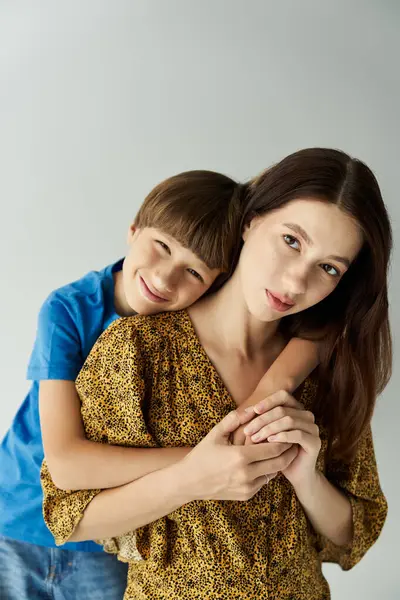 Una joven madre está en un estudio con su hijo, ambos compartiendo un abrazo amoroso. - foto de stock