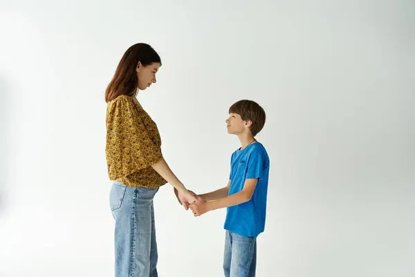A young mother and her son hold hands in a bright studio, sharing a moment of connection. — Stock Photo