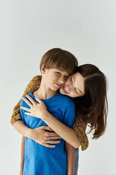 A young mother and her son share a tender hug, expressing warmth and love in a minimalistic studio. — Stock Photo
