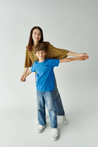 Mother and son embrace happiness together in a modern studio setting while dressed casually. — Stock Photo