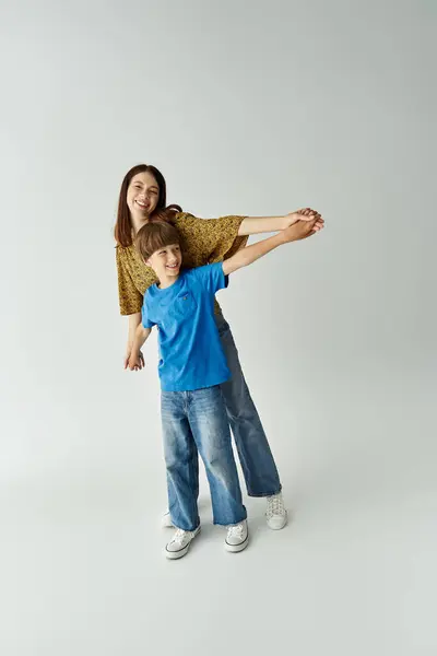 Una joven madre y su hijo están disfrutando de un lúdico vínculo mientras se visten casualmente en un estudio. - foto de stock