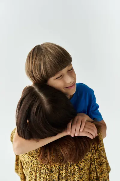 In a modern studio setting, a young mother shares a warm hug with her son, radiating love. — Stock Photo