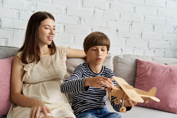 A young mother and her son play with a wooden airplane in their stylish living room. — Stock Photo