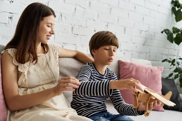 Une jeune mère et son fils jouent avec un avion jouet en bois dans leur salon confortable. — Photo de stock