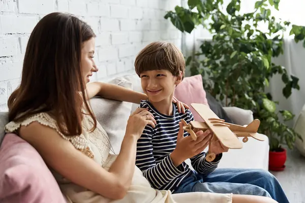 Jeune mère et son fils partagent des moments joyeux tout en jouant avec un avion jouet à la maison. — Photo de stock