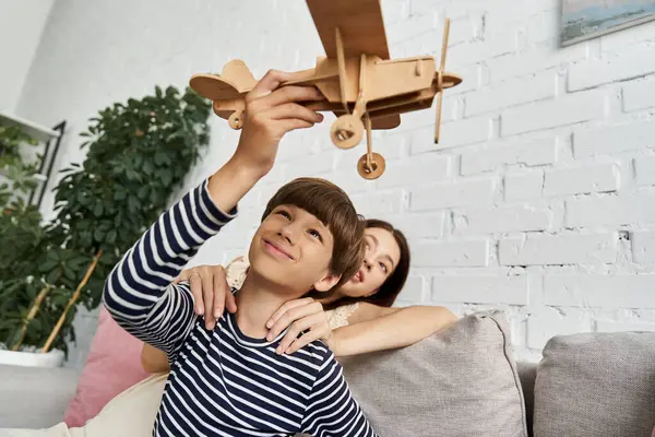 Mère et fils profiter de temps de qualité ensemble jouer avec un avion en bois dans leur salon confortable. — Photo de stock