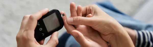A young mother guides her son as he checks his blood sugar, banner — Stock Photo