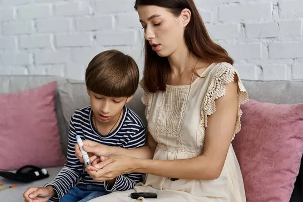 Mother teaches her young son about diabetes management while relaxing at home together. — Stock Photo