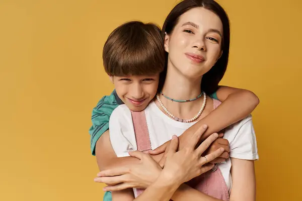 A young mother and her son embrace happily against a bright backdrop, showcasing their bond. — Stock Photo