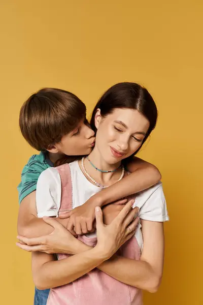 A young mother embraces her son, who kisses her cheek in a joyful display of affection. — Stock Photo