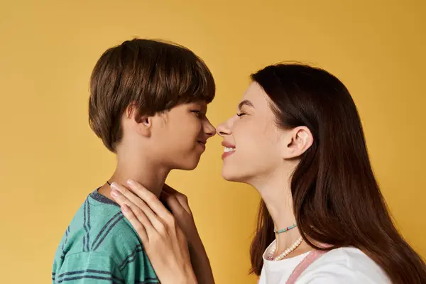A young mother and her son share a playful moment, smiling at each other in a studio. — Stock Photo