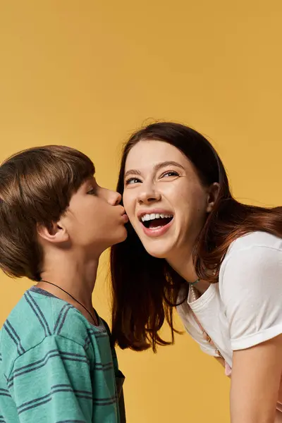 A young mother shares a joyful kiss with her son in a vibrant studio setting. — Stock Photo