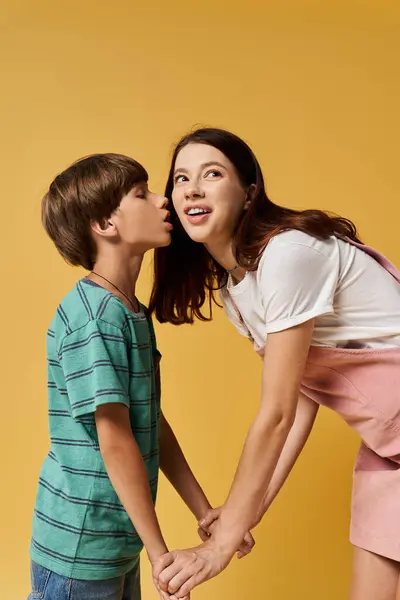 A young mother playfully interacts with her son as they hold hands, showcasing family love. — Stock Photo