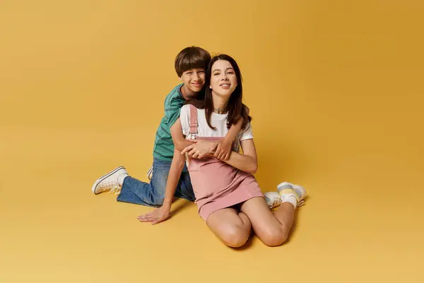 Una giovane madre e suo figlio condividono un momento giocoso, abbracciati in un vibrante studio pieno di calore. — Foto stock