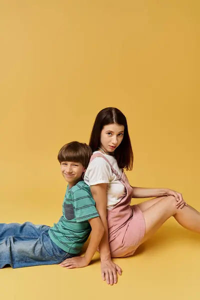 Young mother and her son sit back to back, showcasing comfort and connection in a studio. — Stock Photo