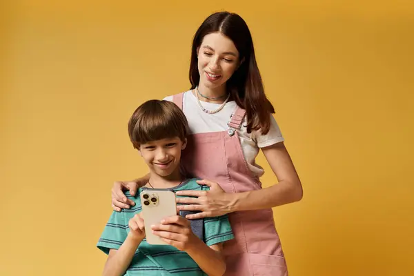 Eine junge Mutter und ihr Sohn verbinden sich freudig über ein Smartphone, was die moderne Elternschaft widerspiegelt. — Stockfoto