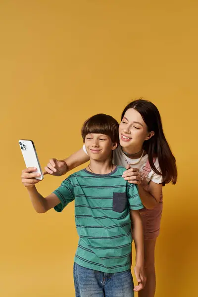 A young mother and her son enjoy taking selfies together, showcasing their playful bond. — Stock Photo