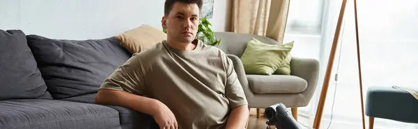 A young man relaxes on a couch, in a bright room at his home. — Stock Photo