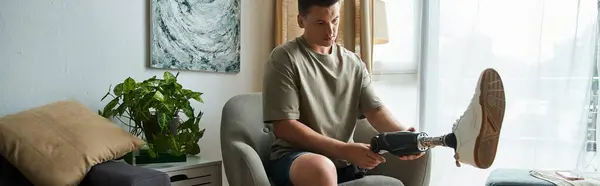 Handsome young man makes adjustments to his prosthetic leg in a modern living space. — Stock Photo