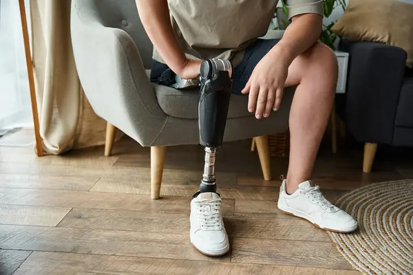 Joven guapo relajándose en una silla, mostrando una pierna protésica mientras usa zapatos casuales. — Stock Photo