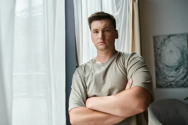 Handsome young man in casual attire stands confidently in a bright room. — Stock Photo