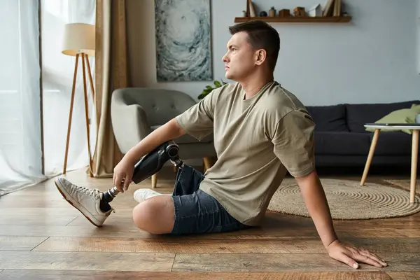 Handsome young man relaxes on the floor, contemplating while next to modern furniture. — Stock Photo