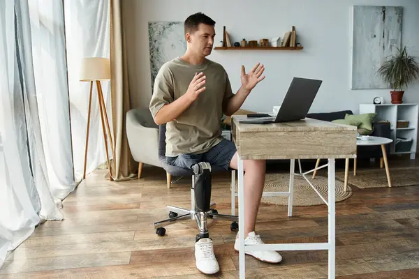 Joven se involucra en una conversación en su computadora portátil mientras está sentado en un entorno hogareño. - foto de stock