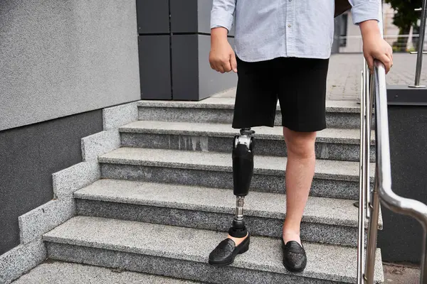 Ein junger gutaussehender Mann geht selbstbewusst mit einer Beinprothese die Steintreppe hinunter. — Stockfoto