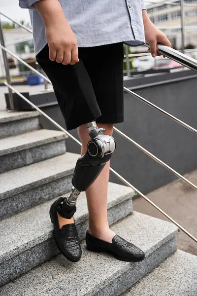 Bonito homem jovem confiantemente sobe escadas ao ar livre usando shorts e sapatos elegantes. — Fotografia de Stock