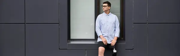A young man stands casually against a minimalist wall, showcasing his prosthetic leg. — Stock Photo