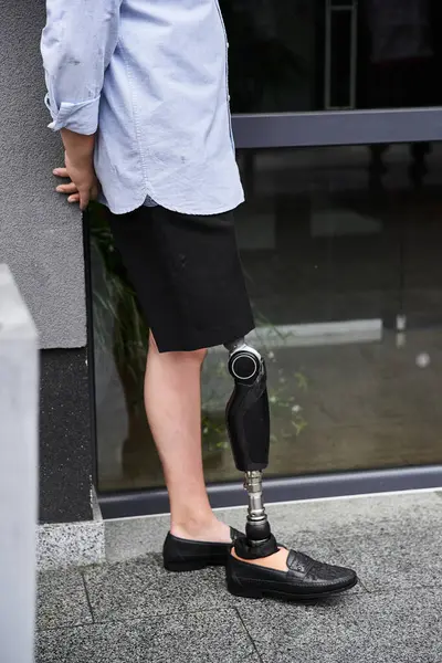 A young handsome man with a prosthetic leg stands outside a modern building, showcasing confidence. — Stock Photo