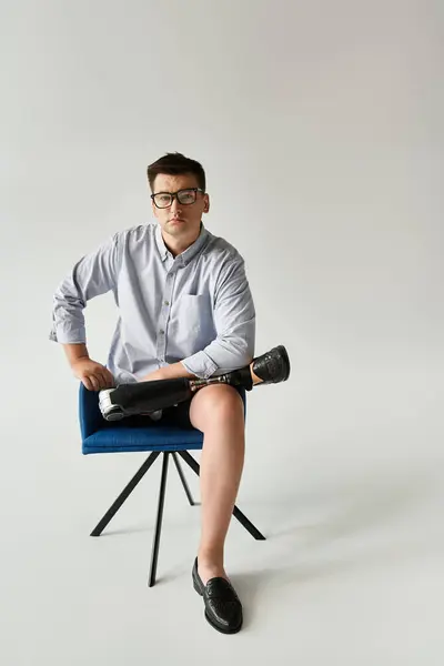 Handsome young man poses confidently on a chair, highlighting his prosthetic leg and style. — Stock Photo