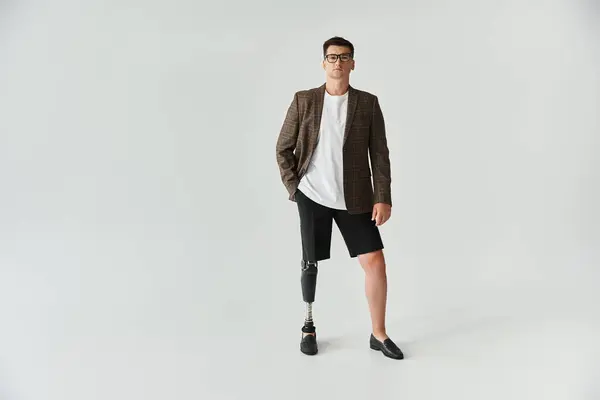 Handsome young man stands in stylish attire showcasing his prosthetic leg with pride. — Stock Photo