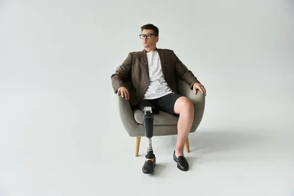 Man sits comfortably in a chair, showcasing a stylish outfit with a prosthetic leg. — Stock Photo