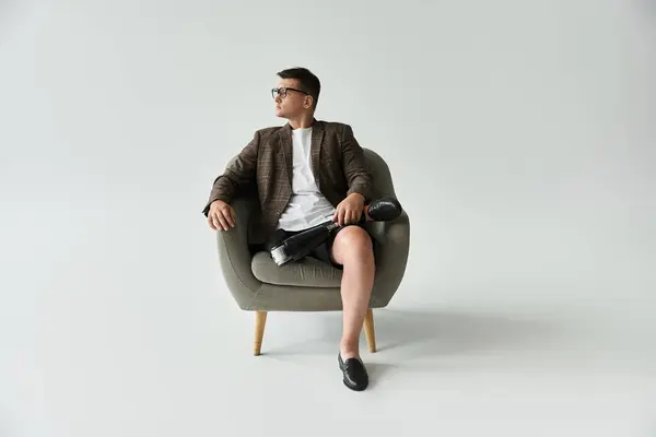 Young man with a prosthetic leg sits comfortably in a modern chair, exuding confidence and style. — Stock Photo