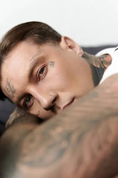 Stylish man with tattoos rests comfortably with a relaxed expression in a casual space. — Stock Photo