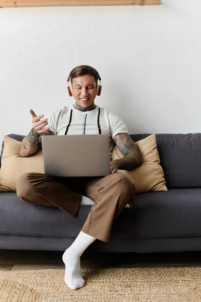 Mann lächelt und gestikuliert während eines Videogesprächs, während er gemütlich auf einer Couch sitzt. — Stockfoto