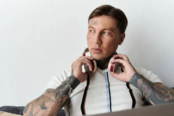 Красивий молодий чоловік з татуюваннями насолоджується музикою в приміщенні під час комфортного відпочинку. — стокове фото