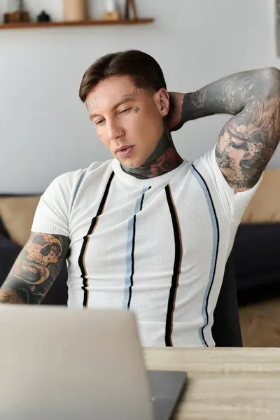 Handsome young man stretches while working on his laptop in a cozy, modern space. — Stock Photo