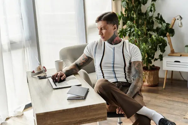 Joven guapo con tatuajes se centró en su computadora portátil en un ambiente de oficina elegante. - foto de stock