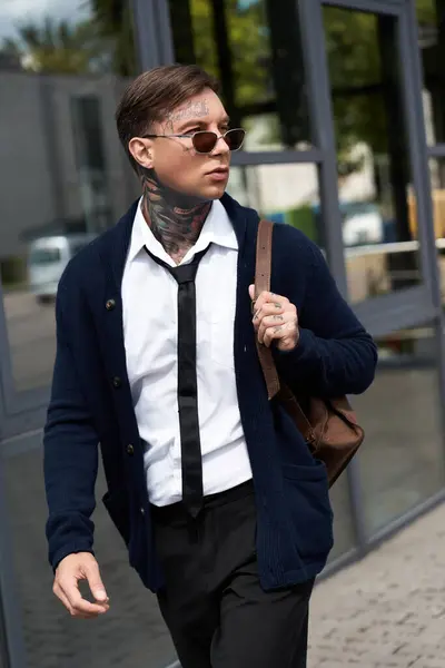 Handsome young man with tattoos walks in a chic outfit, enjoying a sunny day outdoors. — Stock Photo