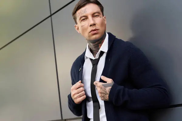 Young man with tattoos displays a stylish look against a modern background in daylight. — Stock Photo