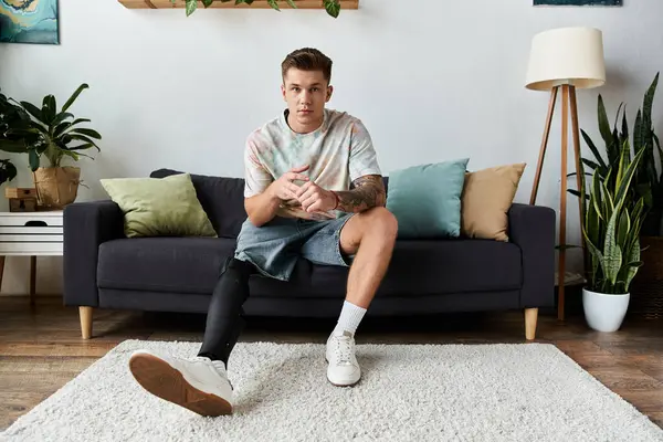 Stylish young man with a prosthetic leg relaxes in a green filled living room. — Stock Photo