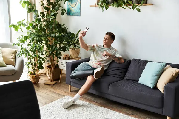 Engaging in a joyful moment, a young man captures a selfie in a stylish living room. — Stock Photo